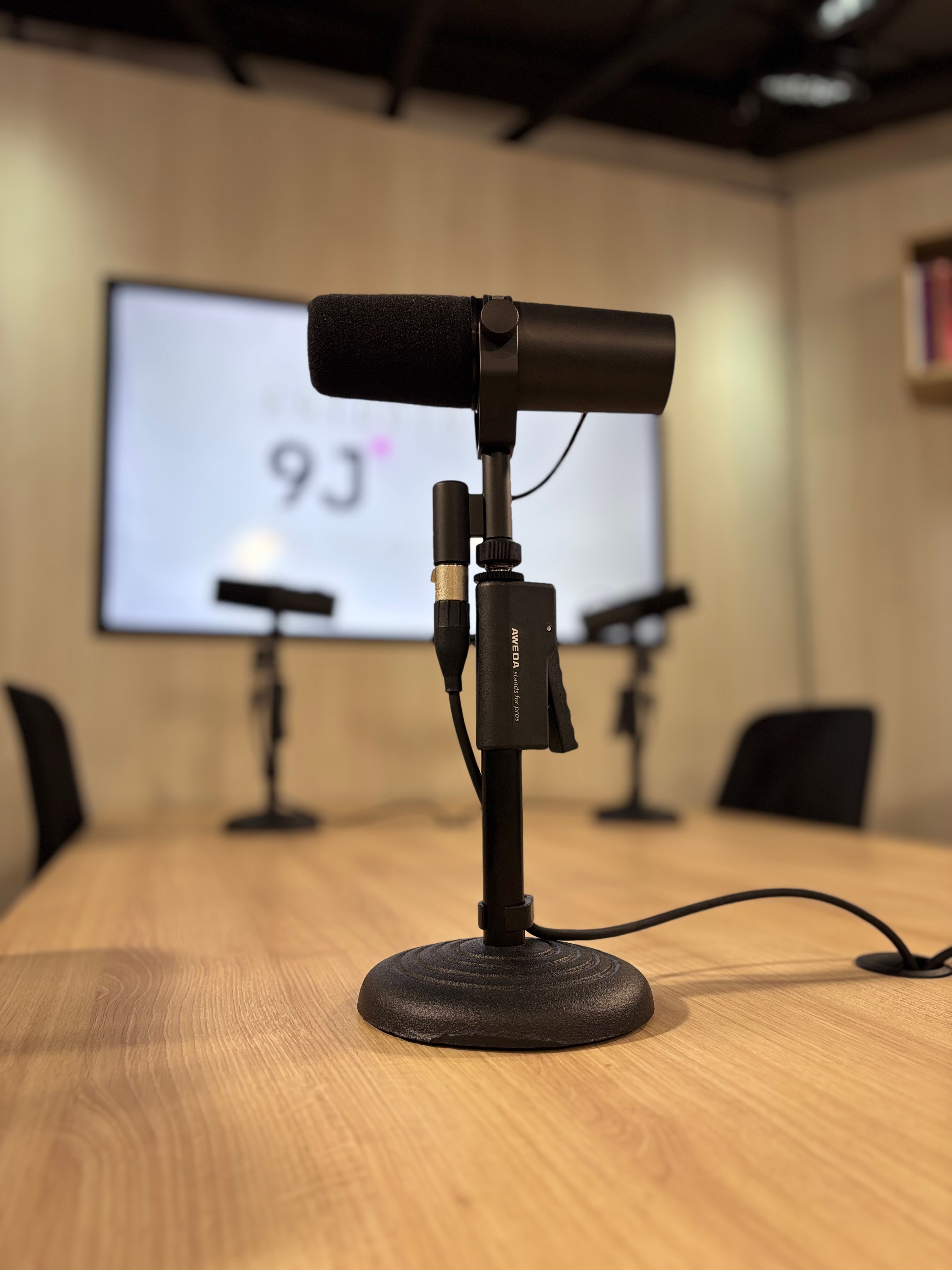 Sala do Estúdio 9J com painéis acústicos, mesa e microfones